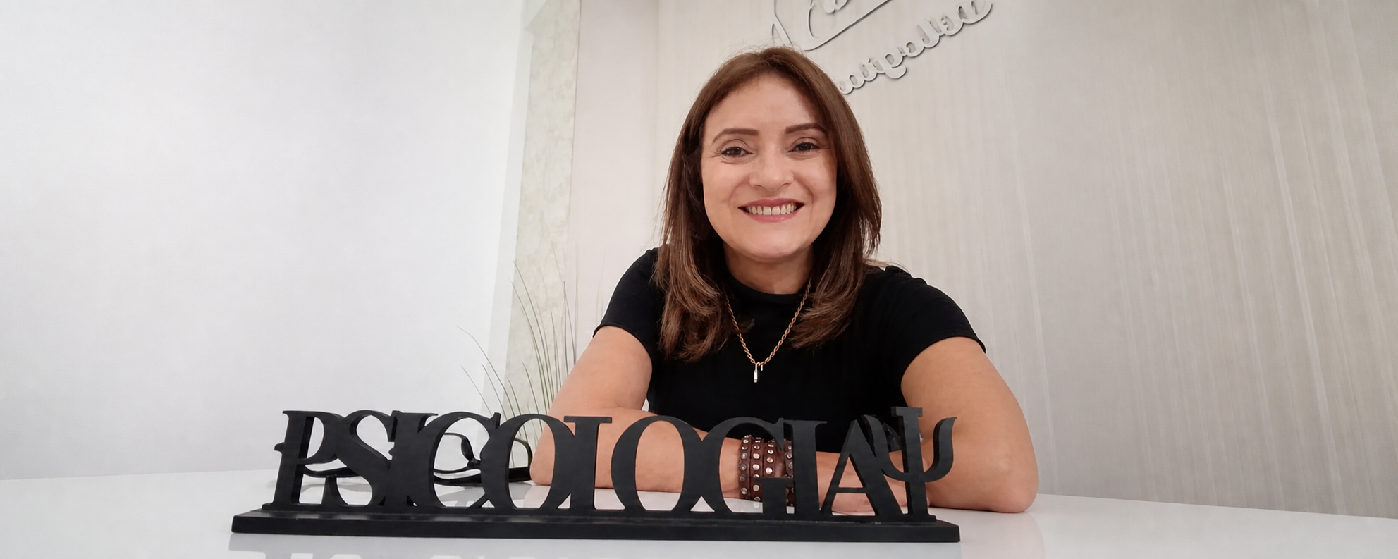 Meire sorrindo em sua mesa de trabalho